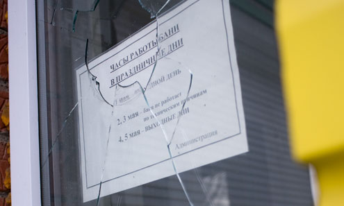 В разбитое окно бани на улице Чехова хорошо видно старое объявление о работе в майские праздники. Не пройдет и полугода, как информация может вновь стать актуальной